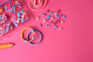 Photo of Handmade jewelry kit for kids. Colorful beads, ribbon and bracelets on bright pink background, flat lay. Space for text