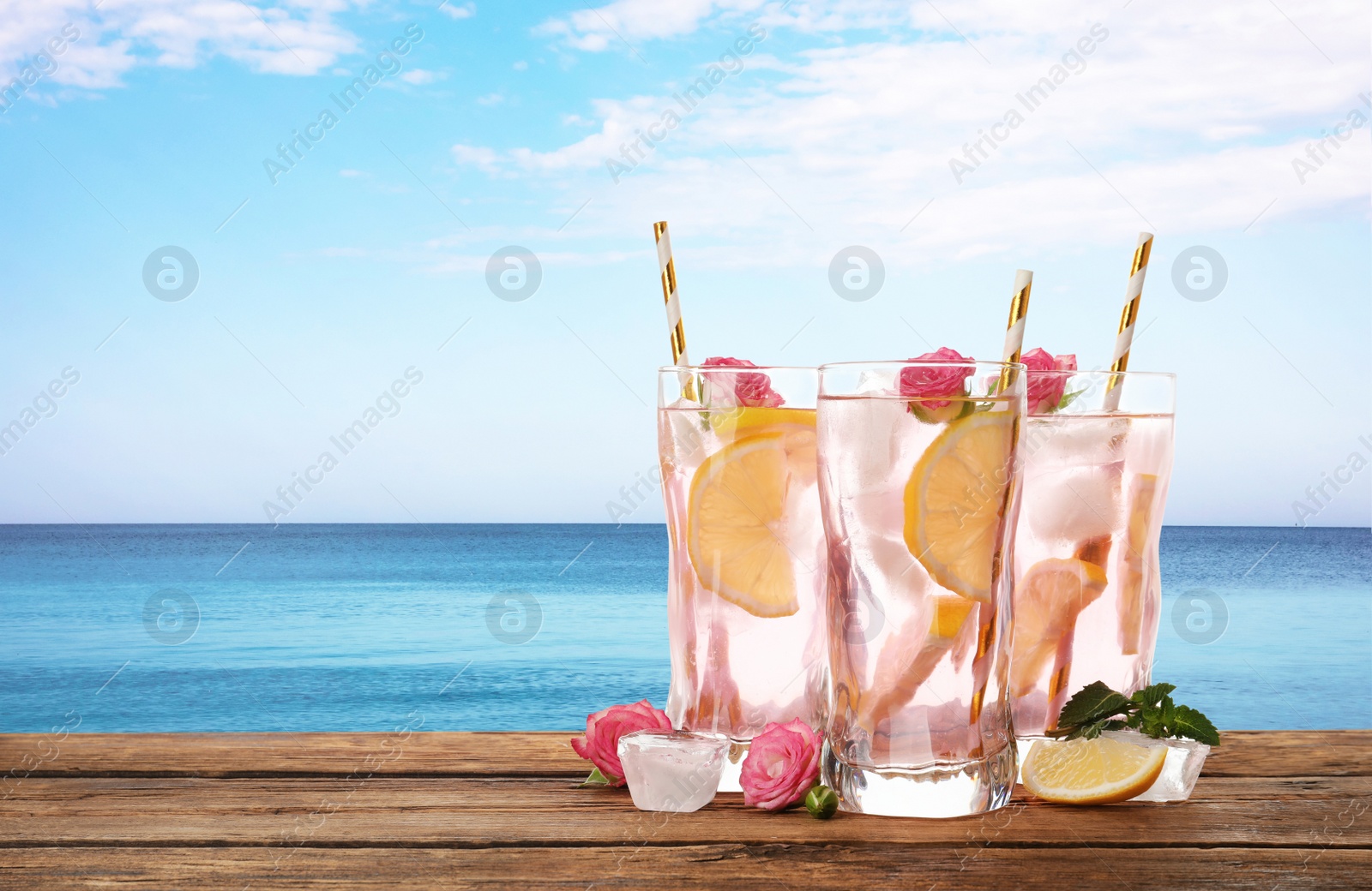 Image of Tasty refreshing drink on wooden table against sea