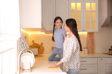 Mother and daughter cleaning up kitchen together at home