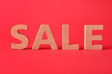 Photo of Word Sale made of wooden letters on red background. Black Friday