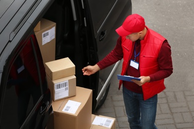 Courier with clipboard and parcels near delivery van outdoors, above view