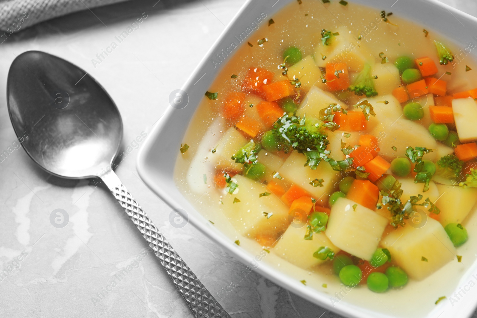 Photo of Bowl of fresh homemade vegetable soup served on grey marble table, closeup