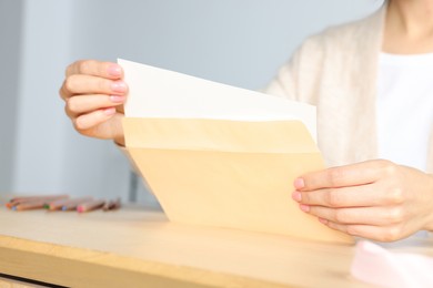 Woman holding greeting card at wooden table, closeup