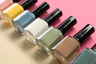 Beautiful nail polishes in bottles on color background, closeup