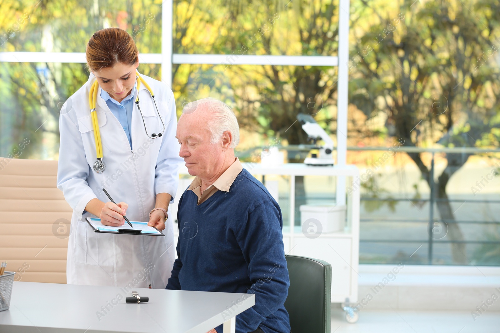 Photo of Doctor working with elderly patient in hospital. Space for text