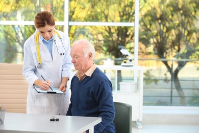 Doctor working with elderly patient in hospital. Space for text