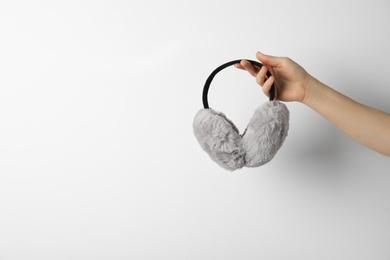 Photo of Woman holding stylish winter earmuffs on white background, closeup. Space for text