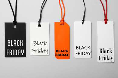 Different tags with text BLACK FRIDAY on light background, flat lay