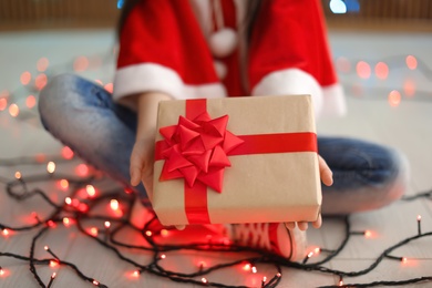 Photo of Cute little child with Christmas gift indoors