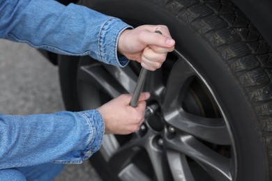 Young man changing tire of car on roadside, closeup