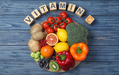 Photo of Cubes with phrase VITAMIN C and fresh products on blue wooden table, flat lay