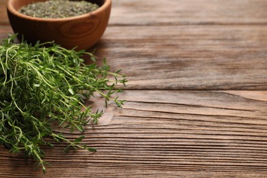 Photo of Bowl with dried thyme and fresh herb on wooden table. Space for text