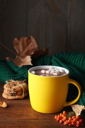 Photo of Cup of hot drink and knitted sweater on wooden table. Cozy autumn atmosphere