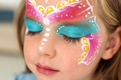 Photo of Cute little girl with face painting indoors, closeup