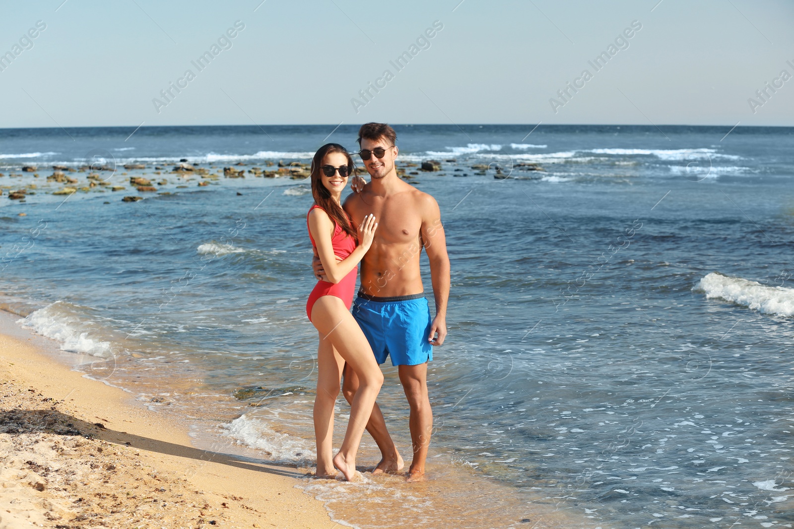 Photo of Happy young couple posing near sea on beach