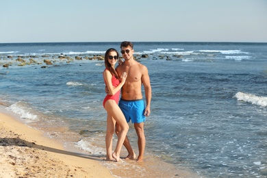 Happy young couple posing near sea on beach