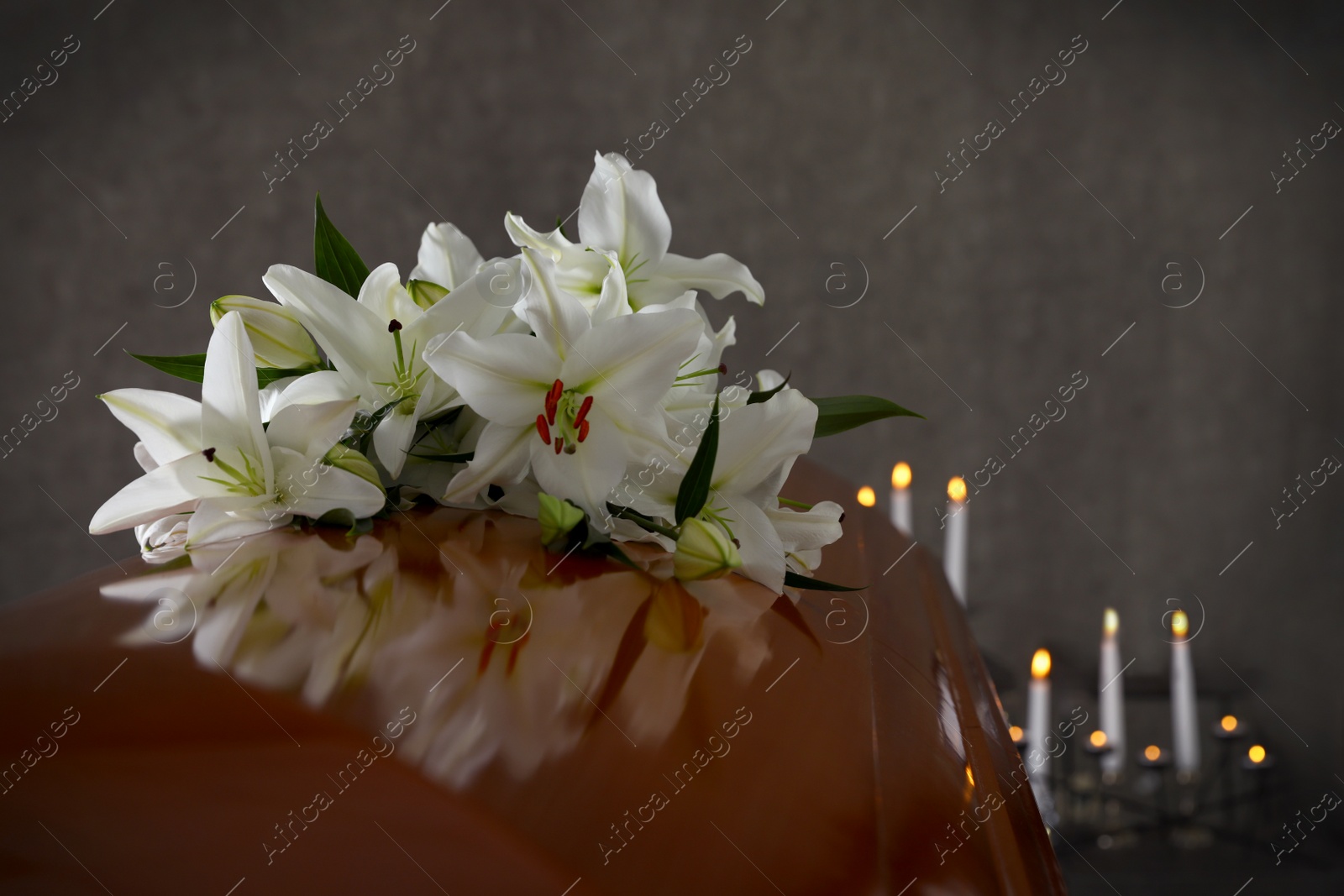 Photo of Wooden casket with white lilies in funeral home, closeup