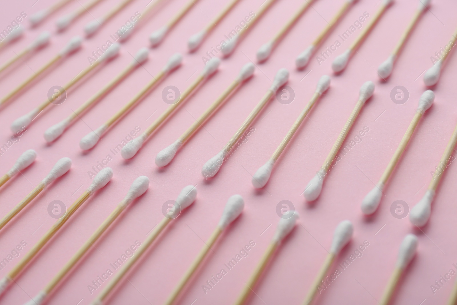 Photo of Many wooden cotton buds on pink background, closeup