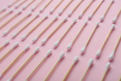 Many wooden cotton buds on pink background, closeup