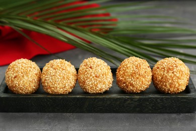 Photo of Delicious sesame balls and green leaf on grey table