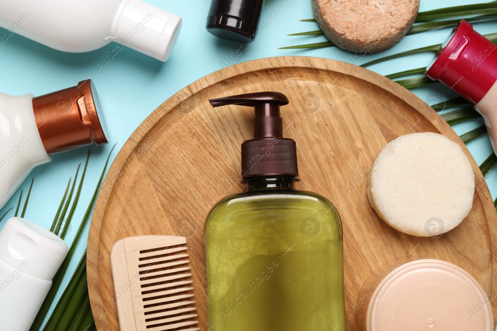 Photo of Shampoo bottles, wooden comb, hair mask and solid shampoo bars on turquoise background, flat lay