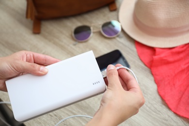 Photo of Woman charging mobile phone with power bank while getting ready for travel, closeup