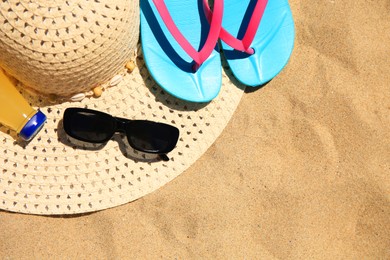 Photo of Straw hat, sunglasses, flip flops and refreshing drink on sand, flat lay with space for text. Beach accessories