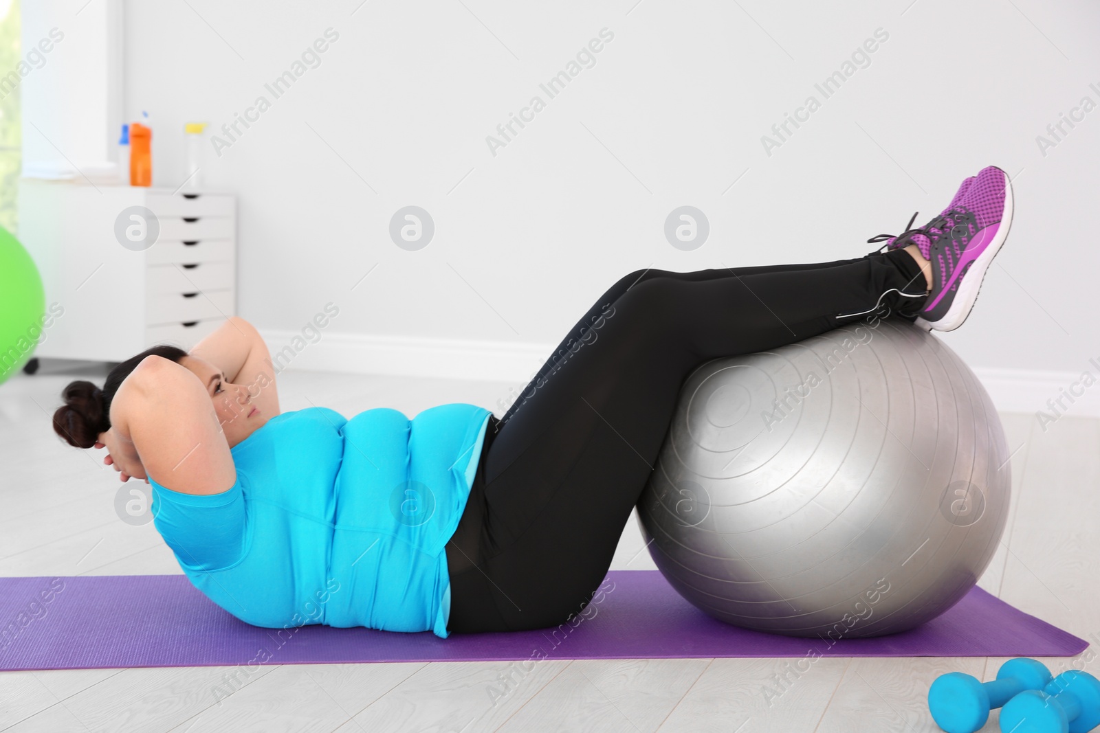 Photo of Overweight woman doing exercise with fitness ball in gym