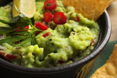 Photo of Delicious guacamole served with nachos chips on table, closeup