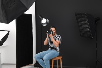 Photo of Young professional photographer taking picture in modern photo studio
