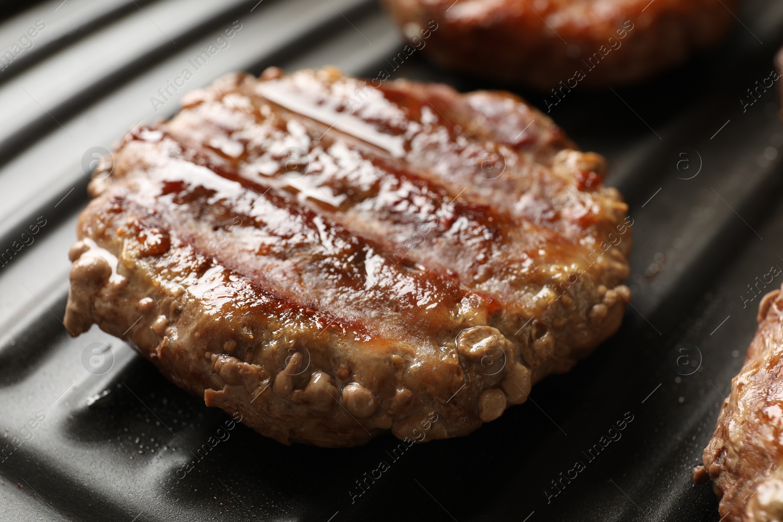 Photo of Delicious hamburger patties cooking on electric grill, closeup