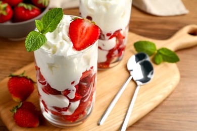Photo of Delicious strawberries with whipped cream served on wooden table, closeup. Space for text