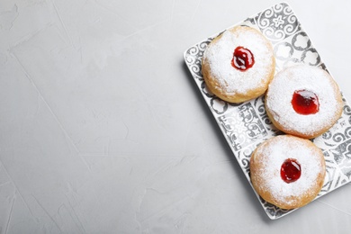 Photo of Hanukkah food doughnuts with jelly and sugar powder served on grey table, top view. Space for text