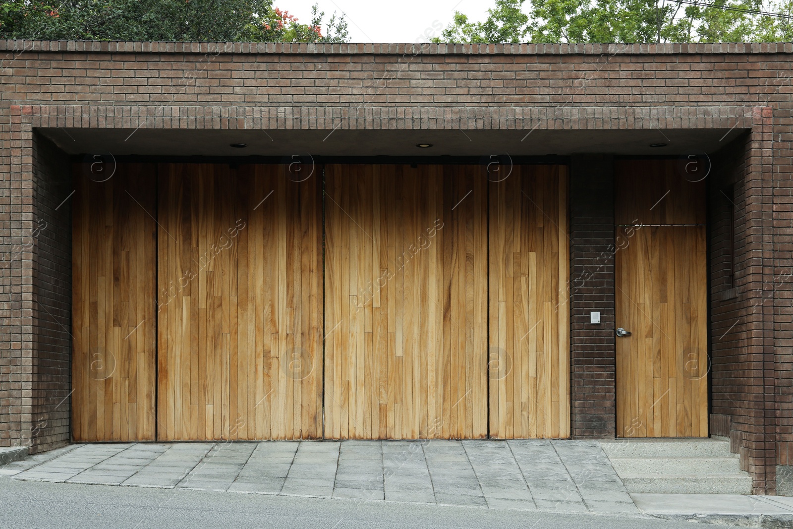 Photo of Brick wall with wooden entrance door and gates. Exterior design