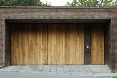 Photo of Brick wall with wooden entrance door and gates. Exterior design