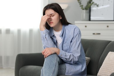 Photo of Overwhelmed woman sitting on sofa at home