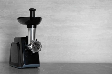 Photo of Modern electric meat grinder on grey table. Space for text