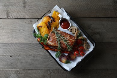 Delicious grilled meat and vegetables served with sauce on wooden table, top view