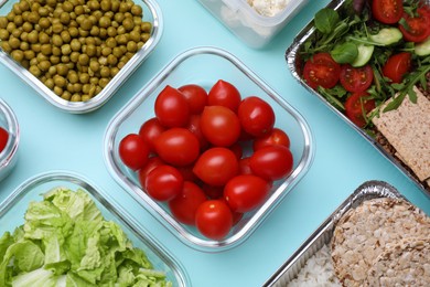 Different containers with fresh products on light blue background, flat lay