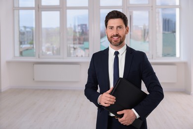 Photo of Happy real estate agent with leather portfolio indoors. Space for text