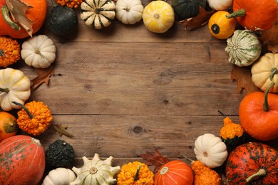 Photo of Frame made of different fresh ripe pumpkins and dry leaves on wooden table, flat lay. Space for text