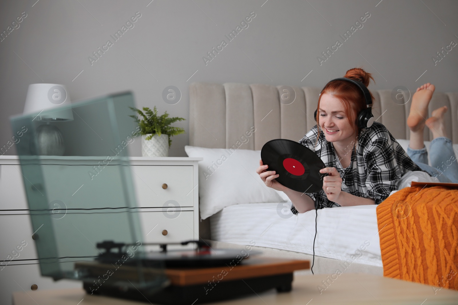 Photo of Young woman listening to music with turntable in bedroom