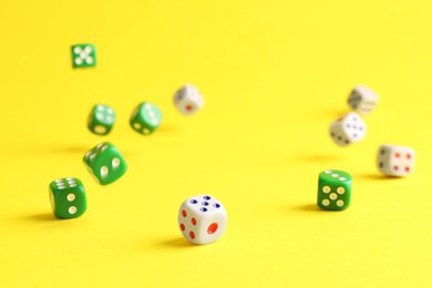 Photo of Many color game dices falling on yellow background