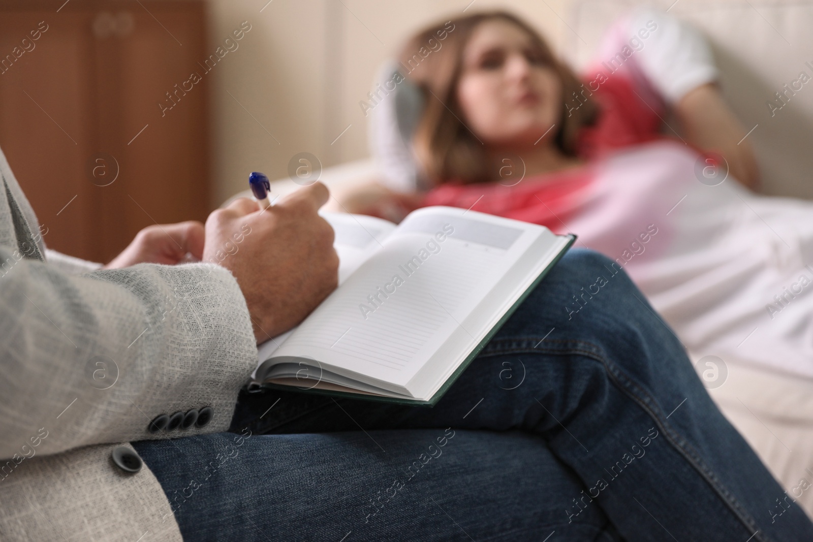 Photo of Professional psychotherapist and patient in office, focus on hands with notebook