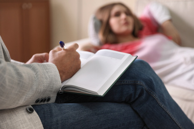 Professional psychotherapist and patient in office, focus on hands with notebook