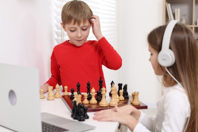 Children playing chess following online lesson indoors