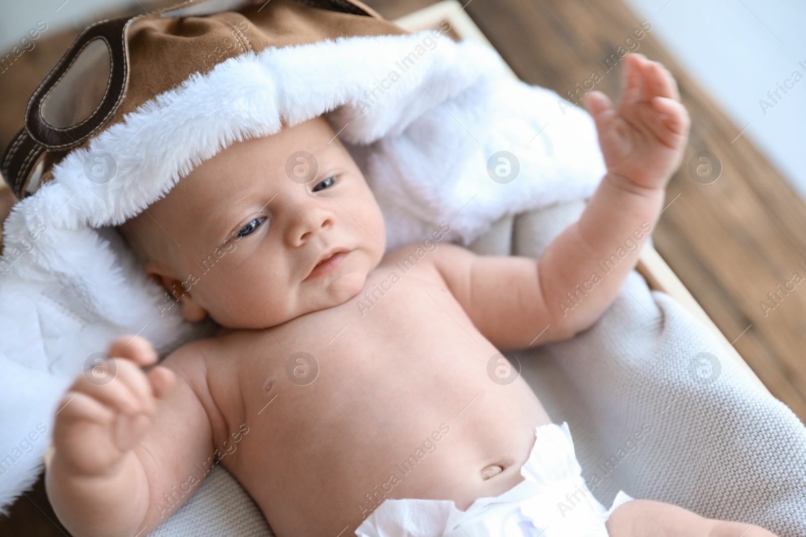 Photo of Cute newborn baby in aviator hat on blanket, closeup