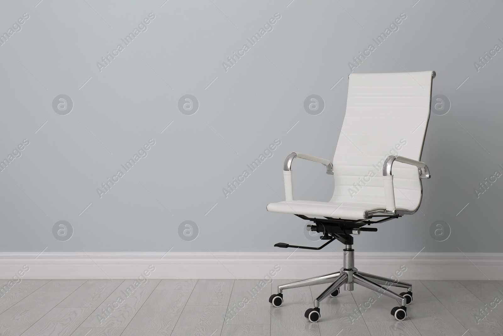 Photo of Comfortable office chair near light wall indoors. Space for text