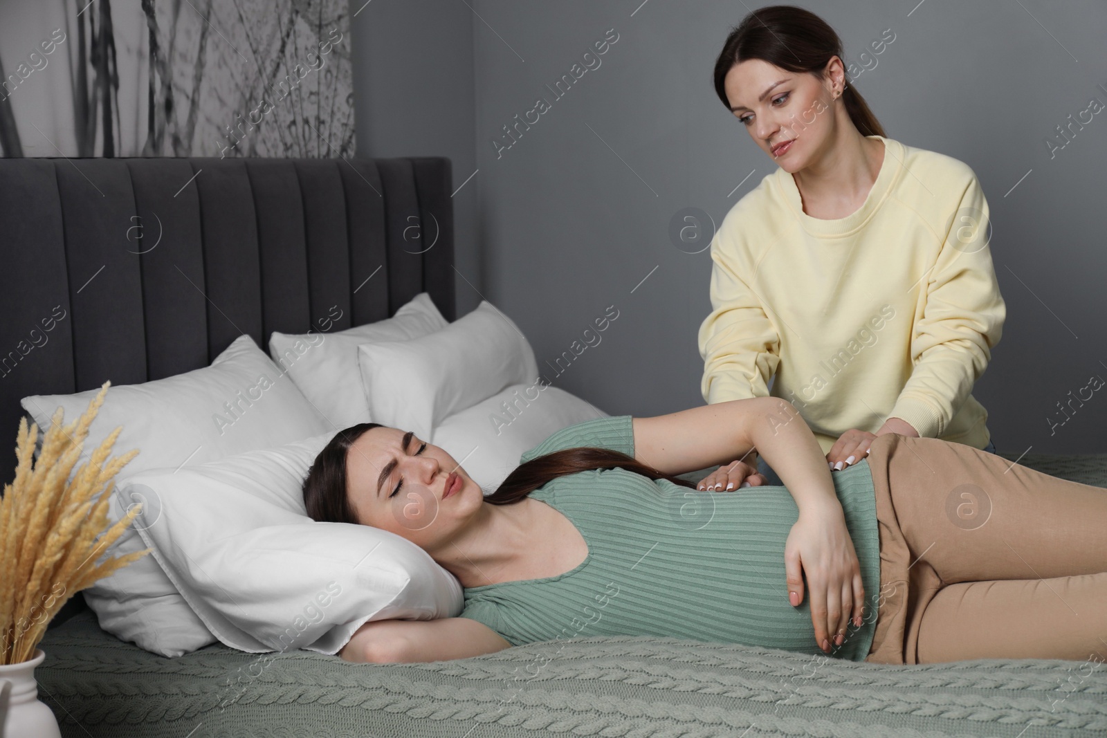 Photo of Doula taking care of pregnant woman in bedroom. Preparation for child birth