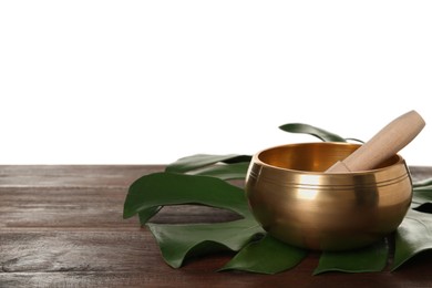 Golden singing bowl, mallet and monstera leaf on wooden table against white background, space for text